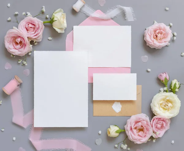 纸卡和信封之间的浅粉玫瑰和丝带灰色的顶部视图 婚礼模型 浪漫的场景 用空白卡片和油腻的花朵 情人节 春天或母亲节的概念 — 图库照片