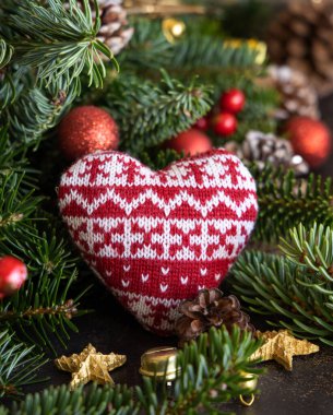 Süslemeler, köknar dalları ve çam kozalakları arasında kırmızı örülmüş kalp yakın çekim, maket. Noel ya da yeni yıl tebrik kartı şablonu, tatil ya da düğün kırtasiyesi