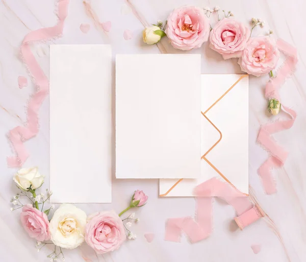 纸卡和信封之间的浅粉玫瑰和丝带的粉色顶部视图 婚礼模型 浪漫的场景与垂直卡片和油腻的花朵平铺在一起 情人节 春天或母亲节 — 图库照片