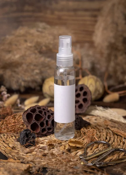 Transparent Refillable spray bottle on wood near natural boho decorations close up label mockup. Skincare beauty product, lotion or essence. Bohemian eco friendly cosmetics flat lay with dried leave