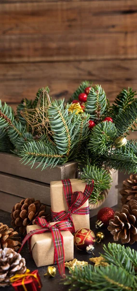 クリスマスの装飾 松のコーンと緑のモミの枝の間に包まれたギフトボックスは 木製の背景に閉じ スペースをコピーします クリスマスまたは新年の休日の雰囲気フラットレイ — ストック写真