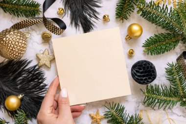 Siyah ve altın noel süslemeleri ve köknar ağacının dalları yanında el ele tutuşma kartı, üst manzara. Boş davetiye kartı ile kış düzlüğü, Mockup, kopyalama alanı