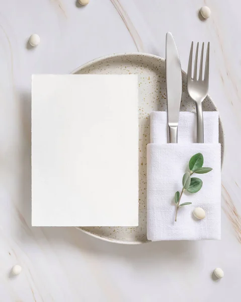 Elegant Table setting with card and envelope decorated with eucalyptus branches  top view, Wedding Mockup. Romantic table with vertical paper card. Close to nature and simplicity concepts