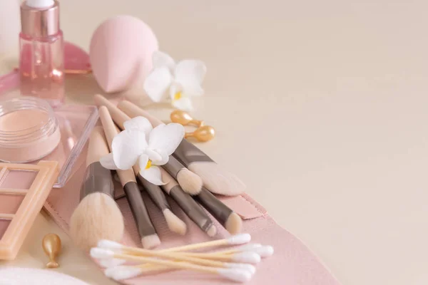 Skin care products and make up brushes on light beige close up, copy space. Natural beauty products and decorative cosmetics. Everyday woman face care routine. Pastel composition