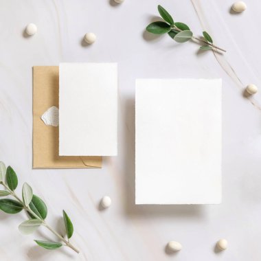 Kartlar ve zarf okaliptüs dalları ve çakıl taşlarının yakınındaki mermer bir masada Mockup. Düğün kırtasiyesi setiyle romantik bir daire. Minimum bileşim. Doğaya yakın. 