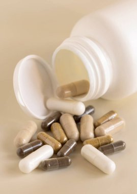 Açık bej bir şişede tıbbi kapsüllerin karışımı. Yakın plan. Koruyucu ilaç ve sağlık, beslenme takviyeleri ve vitaminler. Çeşitli ilaç ilaç kapsülleri.
