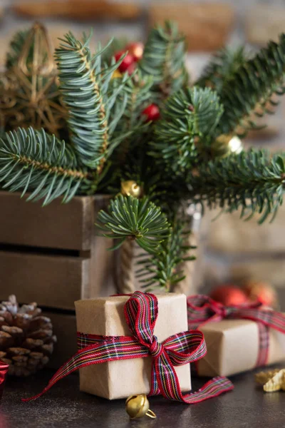 クリスマスの装飾 松のコーンと緑のモミの枝の間にギフトボックスを包んだ暗い背景に閉じます クリスマスまたは新年の休日の雰囲気フラットレイ — ストック写真