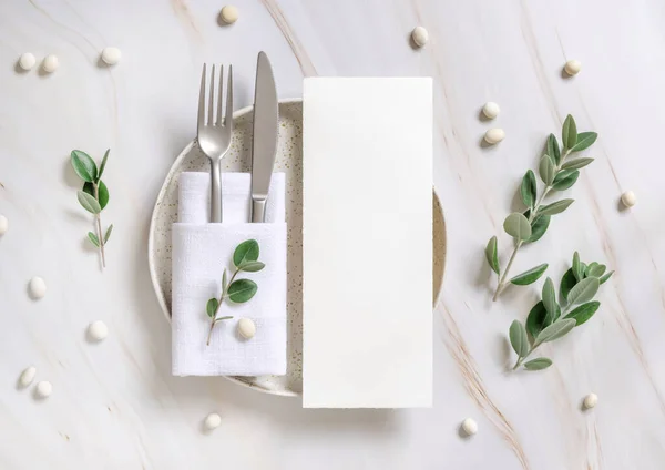 Elegant Table setting with card and envelope decorated with eucalyptus branches  top view, Wedding Mockup. Romantic table with vertical paper card. Close to nature and simplicity concepts
