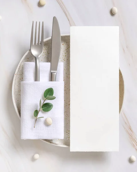 Elegant Table setting with card and envelope decorated with eucalyptus branches  top view, Wedding Mockup. Romantic table with vertical paper card. Close to nature and simplicity concepts