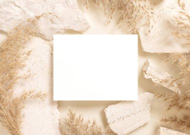 Bej travertin taşlarının yanında boş kart ve kurutulmuş pampa çim üst görünümü, maket. Yatay kartlı Boho sahnesi. Bohem ya da doğaya yakın selamlama ya da düğün davetiyesi. Doğaya yakın.