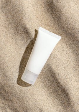 Bej rengi kum tepesi manzaralı beyaz krema tüpü, sert ışık. Paket modeli. Doğal cilt bakımı ya da SPA ürünü. Güzellik rutini için yüz estetiği. Zen stili, kumdaki dalgalar, minimum estetik