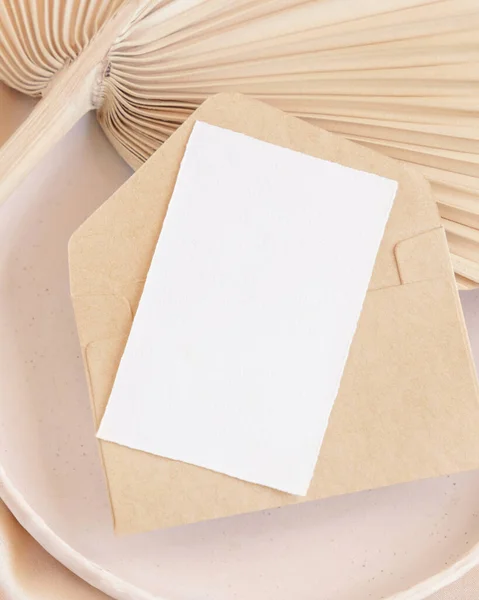 空白卡片和信封与干棕榈叶和米色丝质面料的盘关闭 浪漫的场景与垂直的纸卡 面罩问候语或婚礼接待员 — 图库照片
