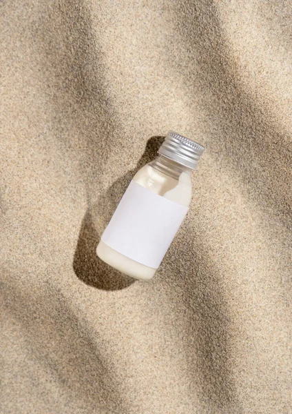 Μπουκάλι Κρέμας Λευκή Ετικέτα Μπεζ Άμμο Πάνω Όψη Σκληρό Φως — Φωτογραφία Αρχείου