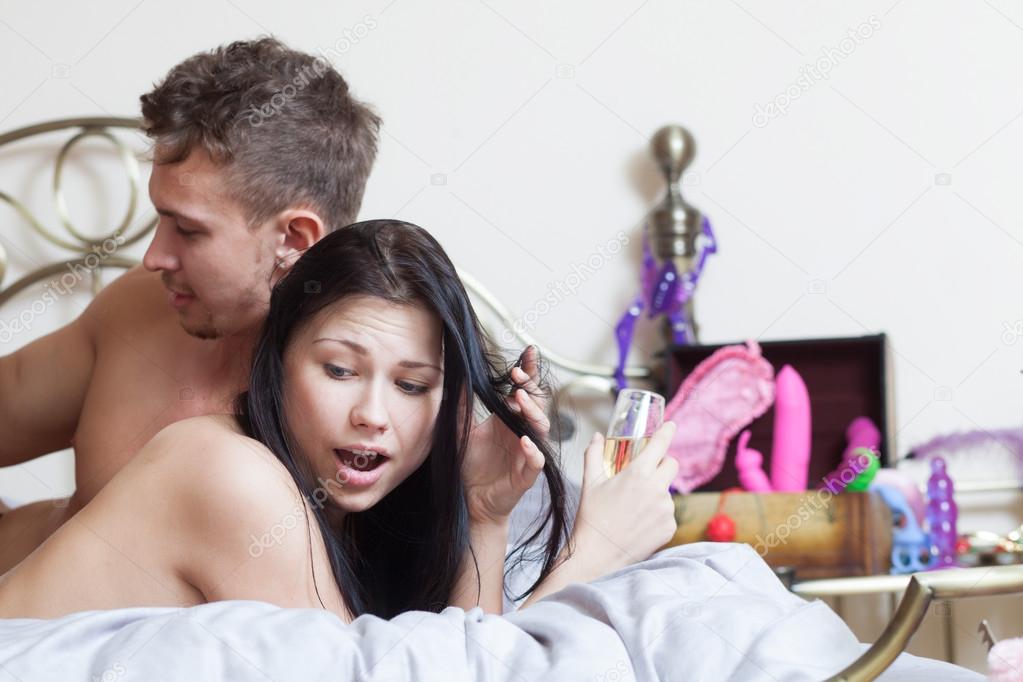 Young couple in bed with sex toys
