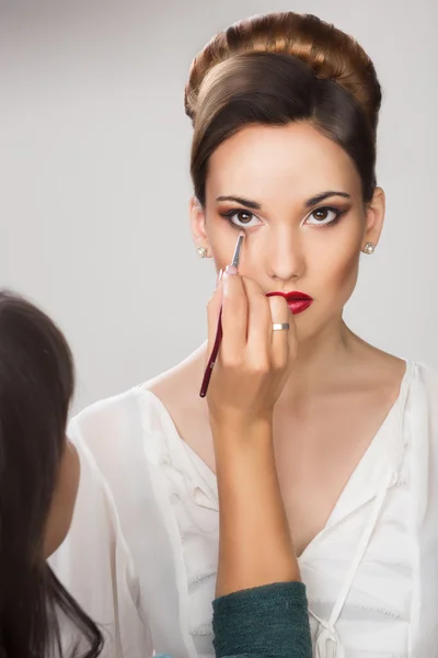 Hermosa chica aplicando maquillaje por maquillador —  Fotos de Stock