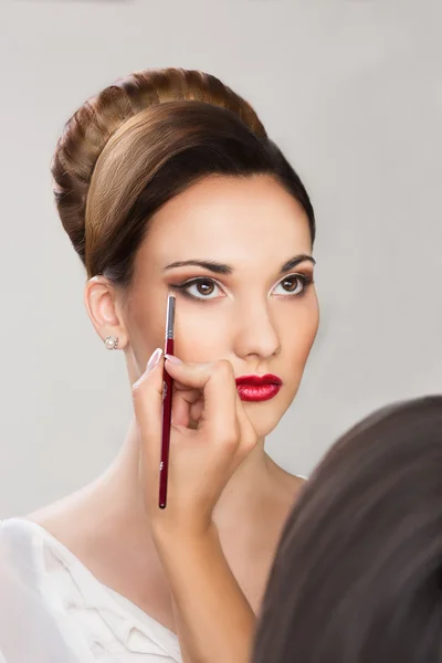 Mooi meisje die van toepassing zijn make-up door make-up artiest — Stockfoto