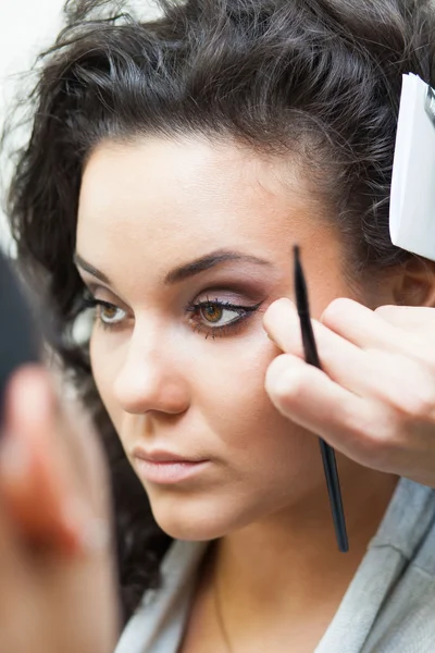 Flicka målar ögon och läppar. makeup. — Stockfoto