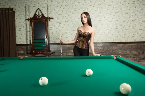 Sexy girl in corset plays billiards. — Stock Photo, Image