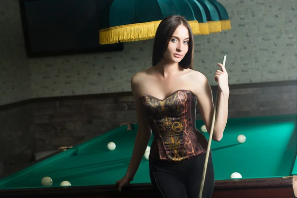 Sexy girl in corset plays billiards. — Stock Photo, Image