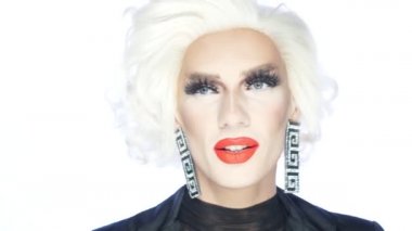 Portre, travesti adam kıpkırmızı dudaklı sarışın beyaz arka planda dans ediyor.