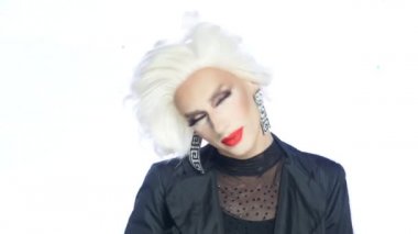 Portre, travesti adam kıpkırmızı dudaklı sarışın beyaz arka planda dans ediyor.