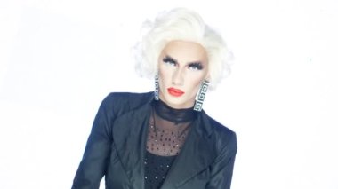 Portre, travesti adam kıpkırmızı dudaklı sarışın beyaz arka planda dans ediyor.