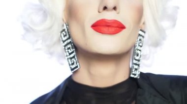 Parodi oyuncusu sarışın, kırmızı dudaklı, mavi gözlü ve çekici makyajlı.