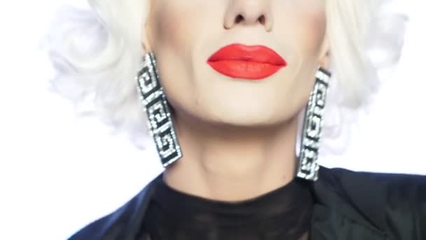 Крупным планом лицо пародийной блондинки с красными губами, голубыми глазами и броским макияжем — стоковое видео