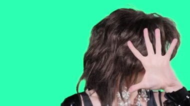 portrait of a handsome travesty actor singing and dancing on a green background
