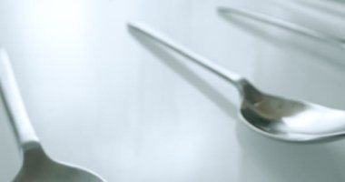 extreme close-up, detailed. large and small stainless steel spoons on a white glossy surface