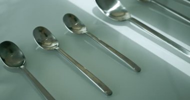 extreme close-up, detailed. large and small stainless steel spoons on a white glossy surface