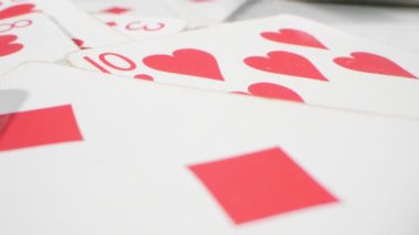extremely close-up detailed, randomly lying playing cards of the red suit of hearts and diamonds