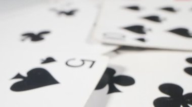 extremely close-up detailed. a queen of hearts among playing cards of spades and clubs, randomly lying on the table