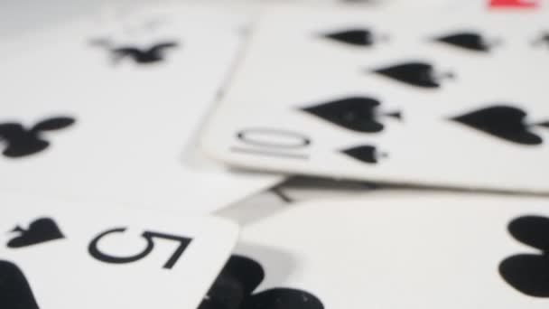 Extremely close-up detailed. a queen of hearts among playing cards of spades and clubs, randomly lying on the table — Vídeo de Stock