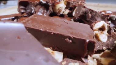 extreme close-up detailed broken pieces of bittersweet chocolate with whole hazelnuts.