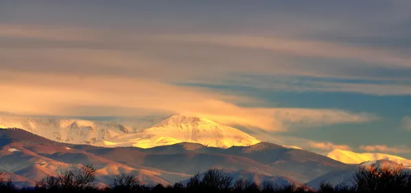 Snötäckta bergstoppar i solnedgången. — Stockfoto