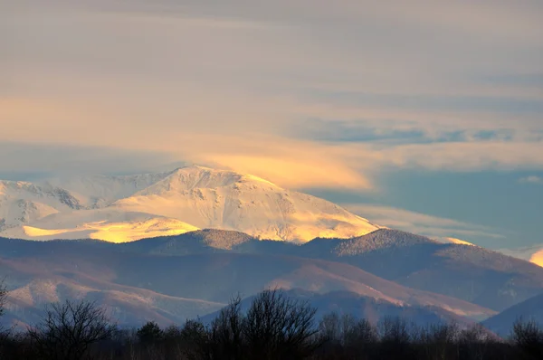 Snötäckta bergstoppar i solnedgången. — Stockfoto