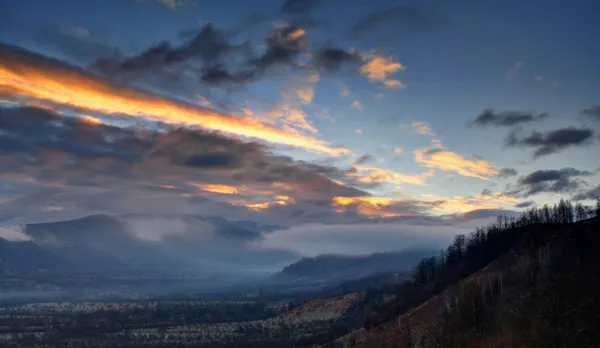 Brume couvrant une montagne au lever du soleil . — Photo