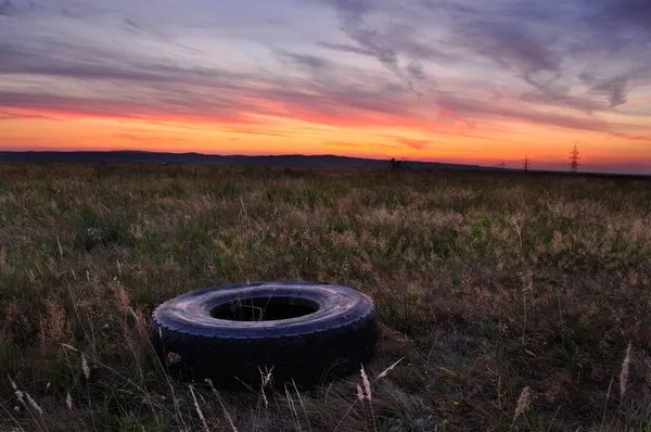 Spätherbstsonnenuntergang mit Reifen auf dem Boden. Platten-Konzept. Stockbild
