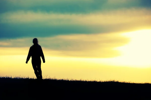 Silhouet van meisje bij zonsondergang. — Stockfoto