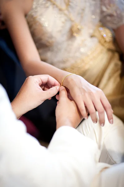 The groom wearing gold bracelet for his bride in wedding ceremony — Stock Photo, Image