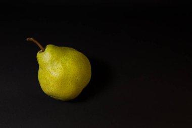 Koyu bir zemin üzerinde olgun yeşil armut, Kasım ayı sonlarında armut çeşitliliği. Tam meyve.