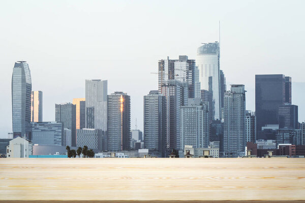 Empty wooden tabletop with beautiful Los Angeles skyscrapers at daytime on background, mock up