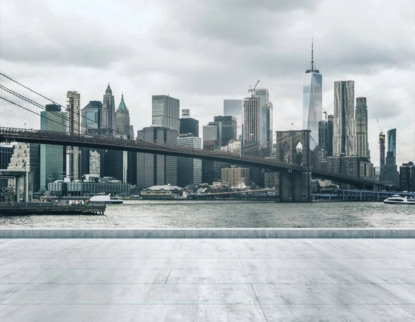 Frente al mar sucio de hormigón vacío en el fondo de un hermoso horizonte de la ciudad de Nueva York y el puente de Brooklyn durante el día, se burlan de — Foto de Stock