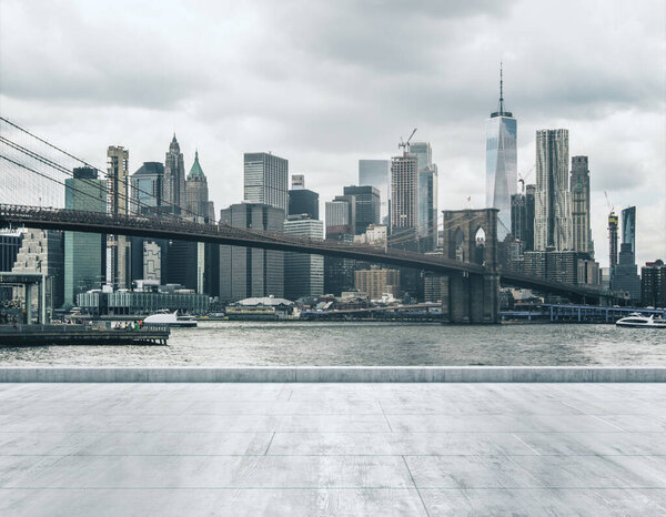 Empty concrete dirty seafront on the background of a beautiful New York city skyline and Brooklyn bridge at daytime, mock up