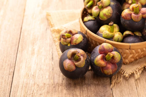 Ahşap masa arkasındaki mangosteen yığınını kapat. Gıda ve sağlık konsepti