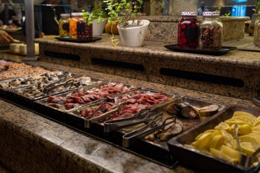 Breakfast buffet with different kinds of fish and lemon slices at a hotel in Israel. Select focus on one kind of fish.