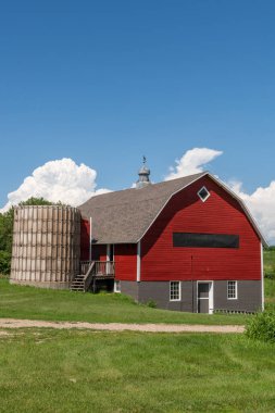 Kahverengi kiremitli çatılı kırmızı ahır ve Minnesota, ABD kırsalındaki bir çiftlikte eski silo..