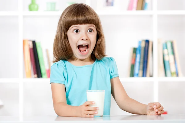 Bambina con bicchiere di latte che fa un viso — Foto Stock