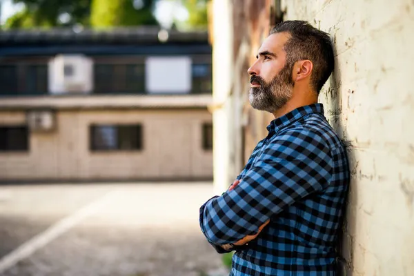 レンガの壁の屋外の前に立っている間 ひげを考えながら心配ビジネスマンの肖像画 — ストック写真